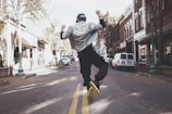 man jumping on the middle of the street during daytime
