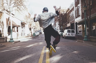 man jumping on the middle of the street during daytime
