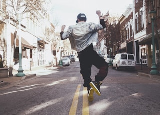 man jumping on the middle of the street during daytime