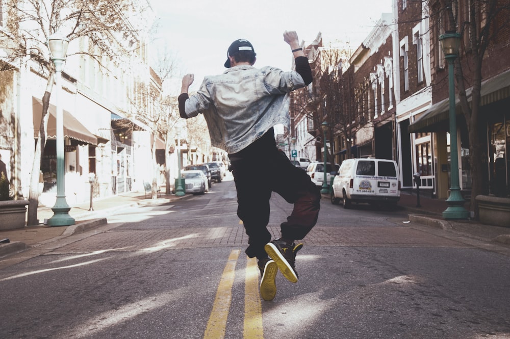 man jumping on the middle of the street during daytime