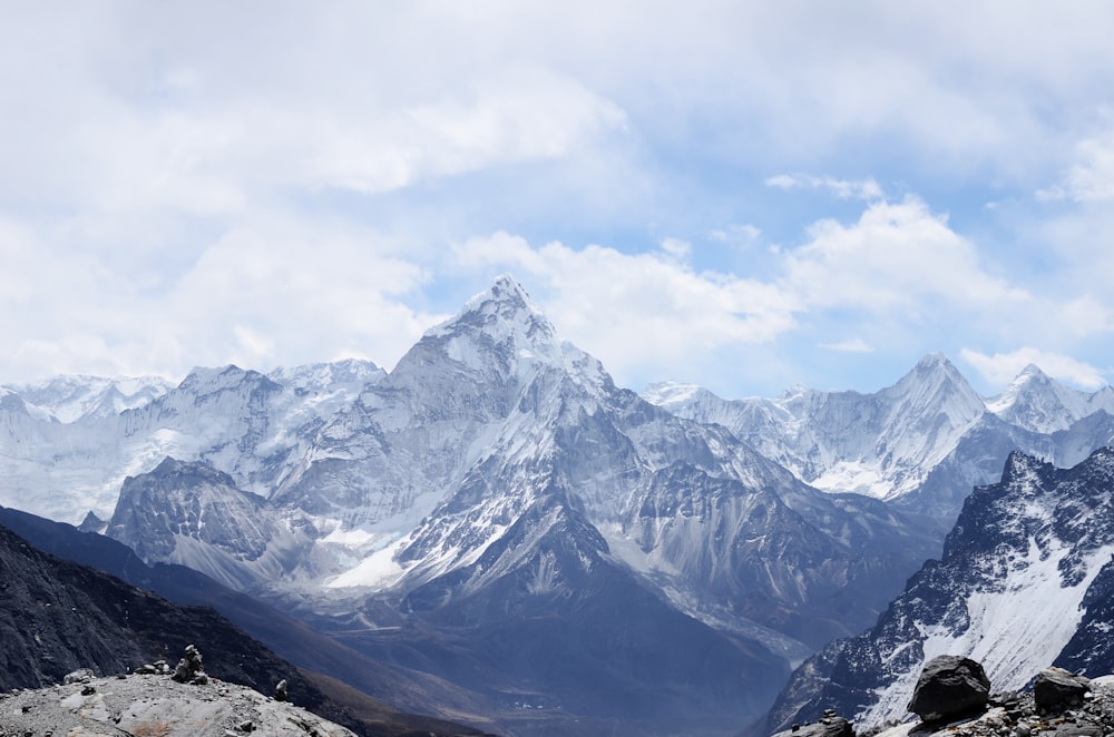 Photographie aérienne d’une chaîne de montagnes recouverte de neige sous un ciel blanc et bleu de jour