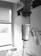 A close-up view of an intravenous drip chamber filled with liquid, in a clinical setting with hospital equipment and a window visible in the background. The image is in black and white, emphasizing the medical and sterile environment.
