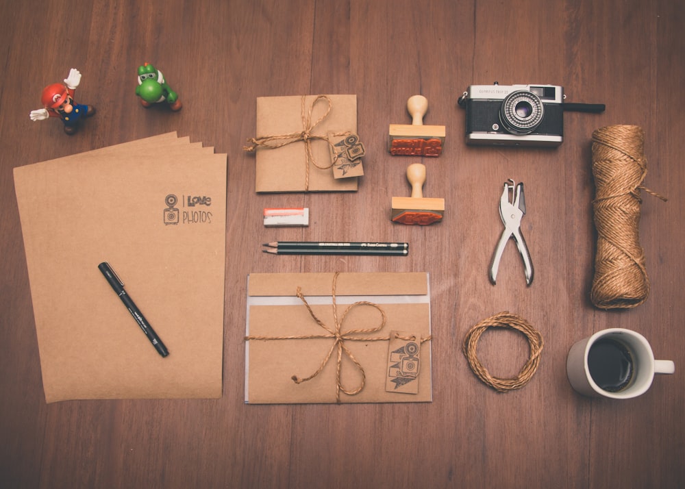 Fotografía plana de papel de impresora marrón, taza, lápiz y cámara