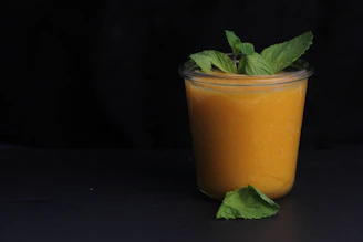Creamy smoothie in a glass jar topped with fresh fruit and a sprig of mint.