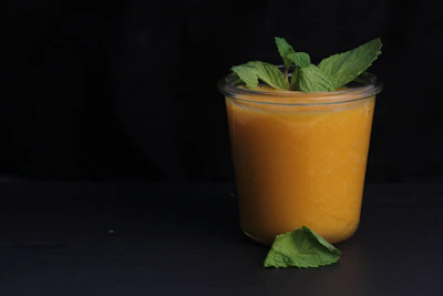 Bright lime green smoothie in a glass jar surrounded by fresh herbs