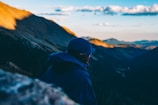 Evening shot of a man wearing t-boy jacket overlooking a mountainous landscape.
