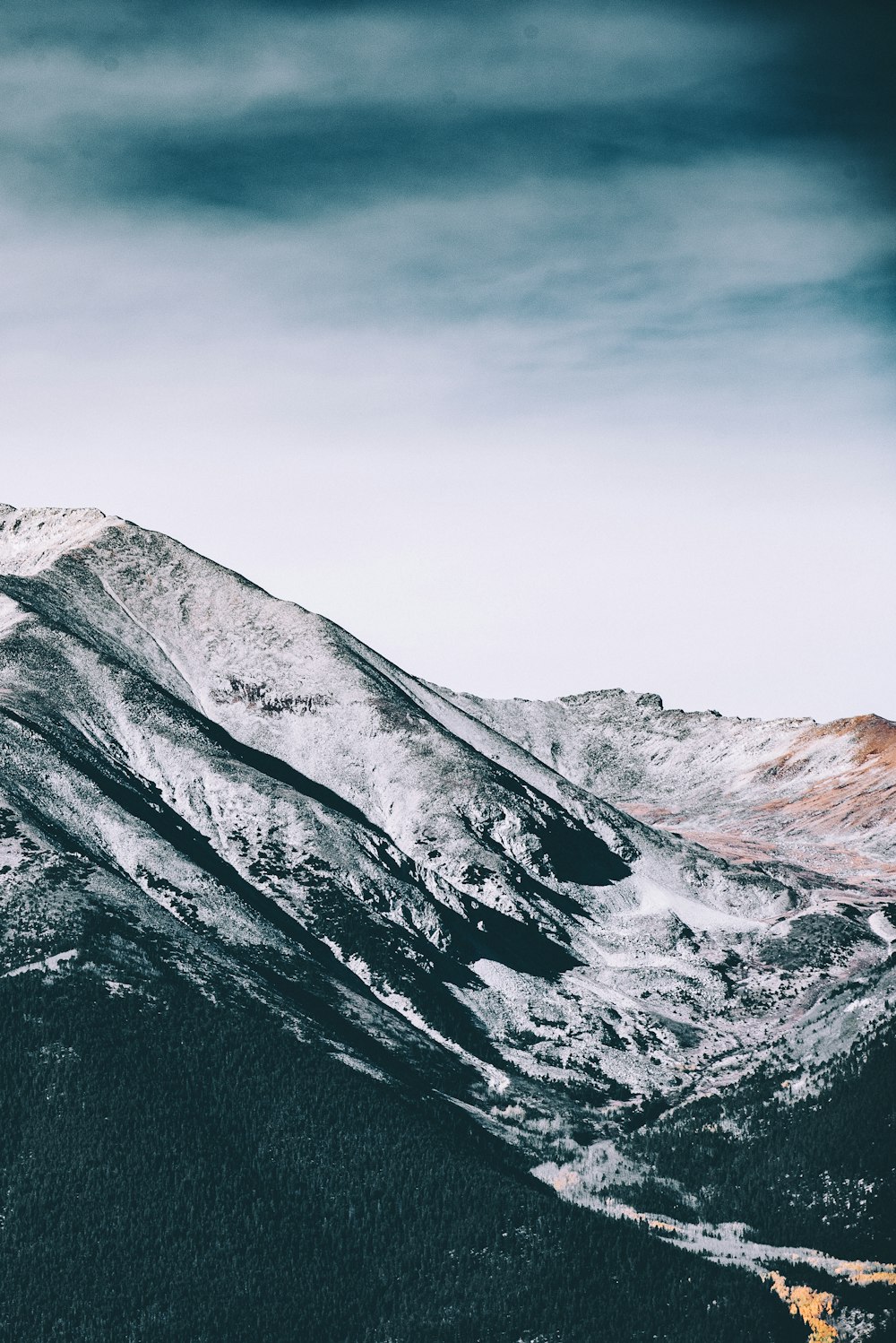 grey and brown rocky mountain under white and dark sky