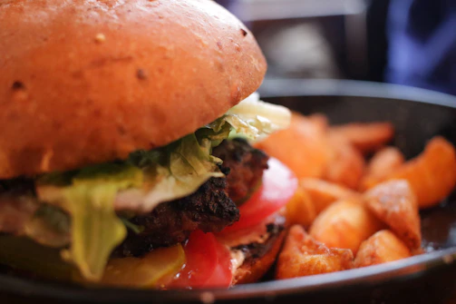 Top view of a juicy burger with caramelized onions and a side of golden fries.