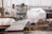 A docked boat labeled 'Freundschaft' is surrounded by various covered structures. The scene includes a mix of maritime equipment, industrial elements, and partially constructed or repaired vessels. The atmosphere is calm and industrious, suggesting a shipyard or harbor setting.