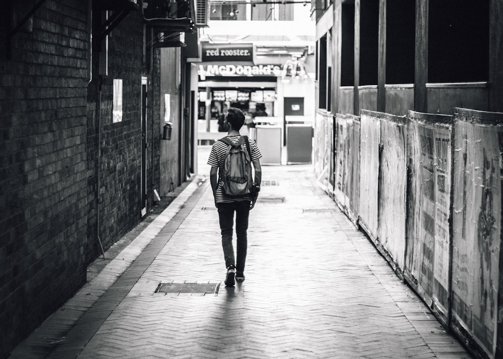 man walking between concrete buildings