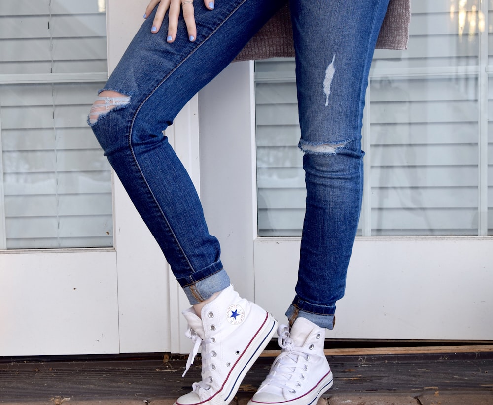 Blaue Denim-Jeans im Used-Look für Damen und weiße Converse Allstar High-Tops