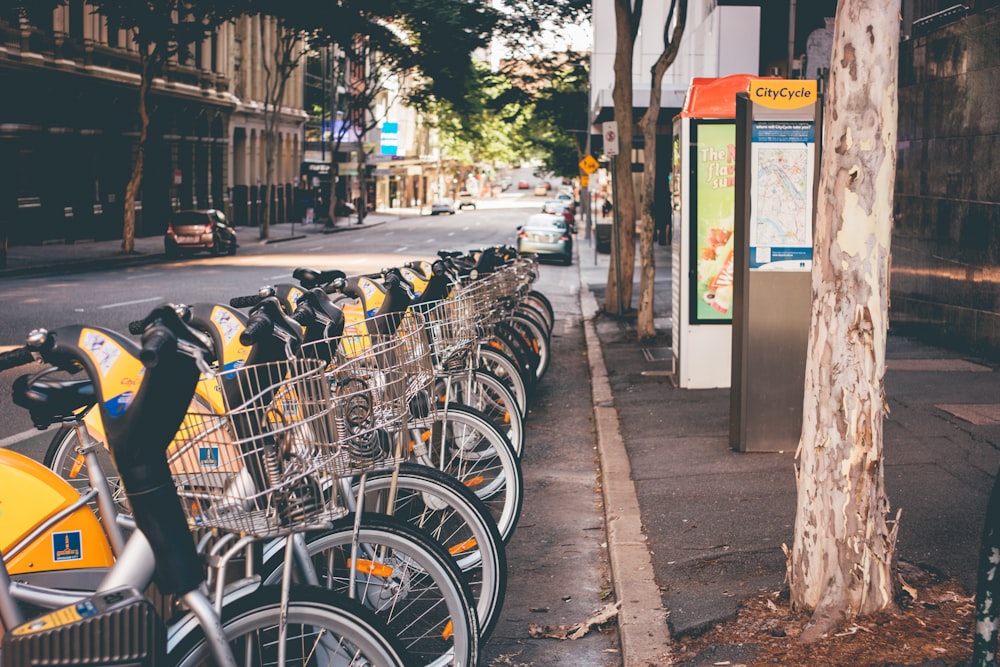 assorted commuter bicycle park ahead near yellow car at daytime