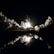 A space shuttle is launching amidst a dramatic night setting. Thick clouds of smoke billow around the illuminated launch pad, with the flames of the shuttle's engines reflecting in a body of water below. The dark sky contrasts with the bright light from the launch.