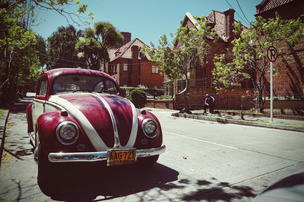 red and white Volkswagen Beetle on road near brown house