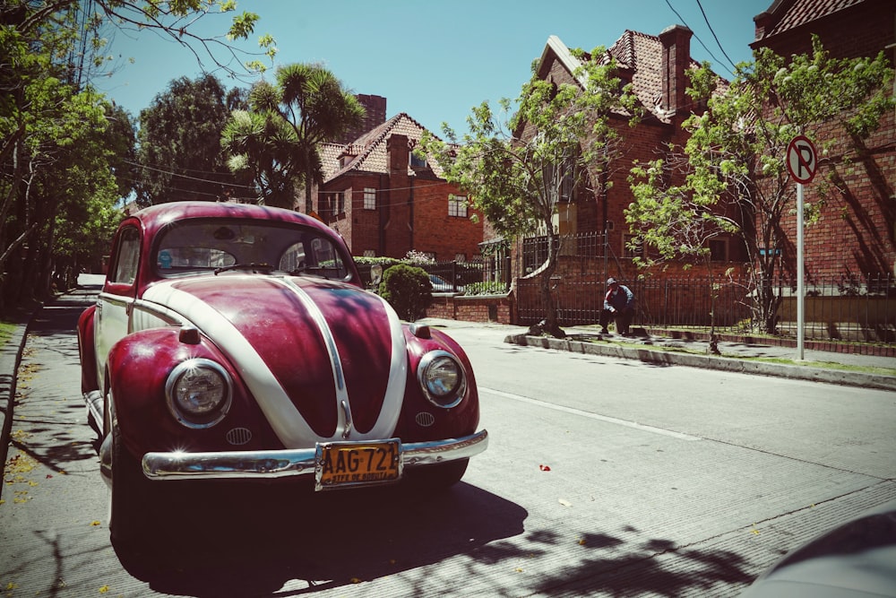 Volkswagen Beetle rojo y blanco en la carretera cerca de la casa marrón