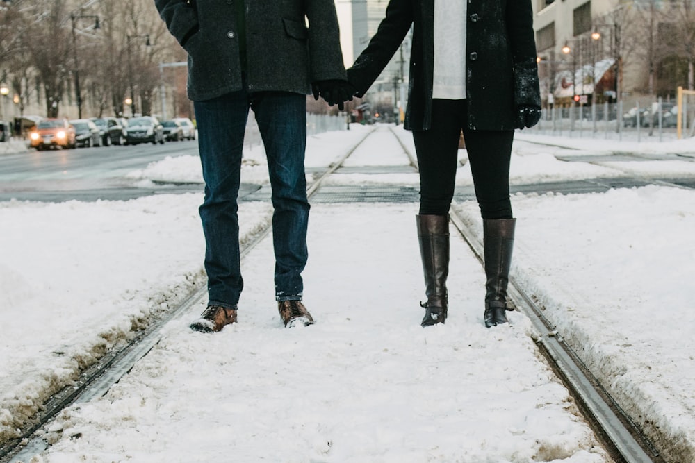 photo of two person standing on snow-covered road