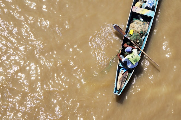 man sitting on blue boat on water