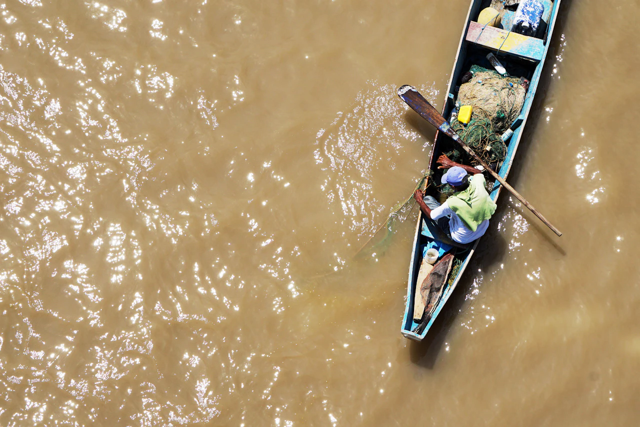 A fisherman in a blue boat on the water at Guayaquil, seen from above