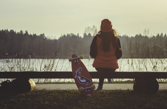 Woman sitting on a bench with her longboard nearby