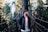 man standing on bridge in forest during daytime