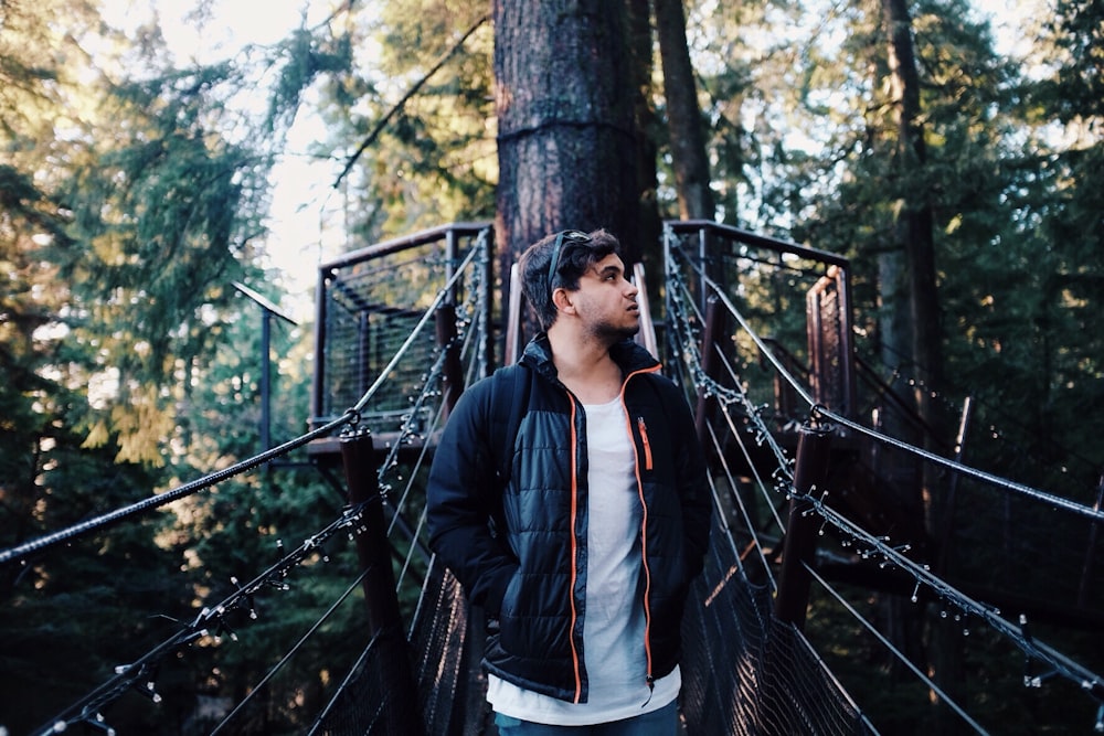 man standing on bridge in forest during daytime