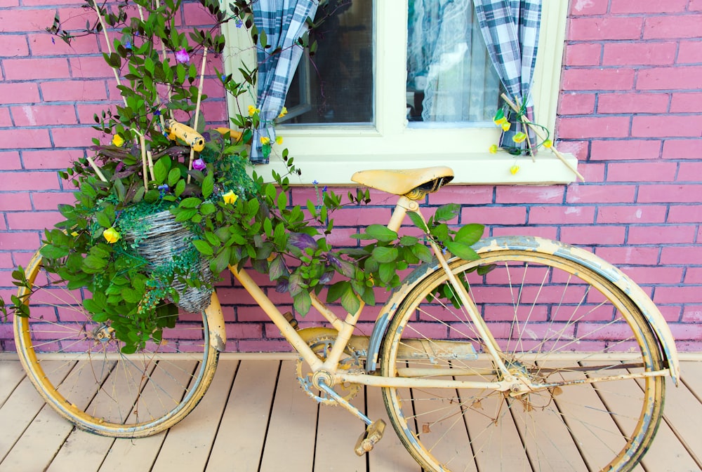 bicicleta marrom da cidade com flores perto do edifício de tijolos vermelhos durante o dia