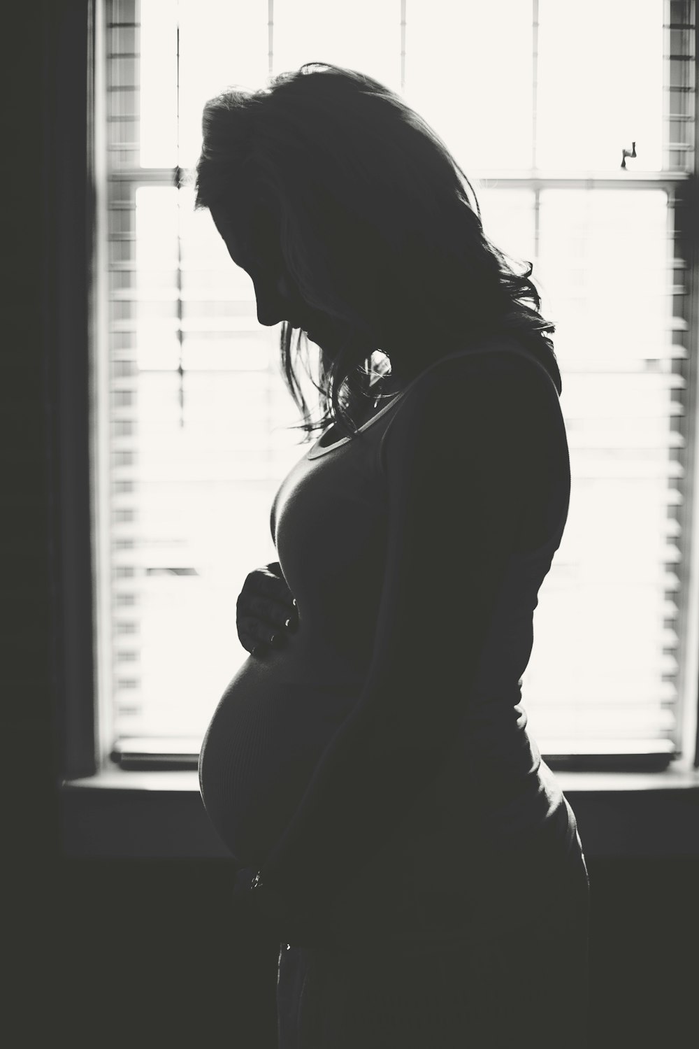femme enceinte debout à l’intérieur de la pièce pendant la journée