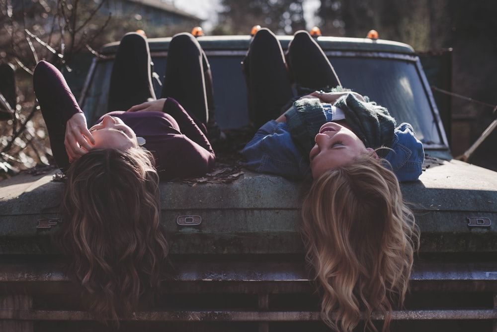 two women lying down on vehicle