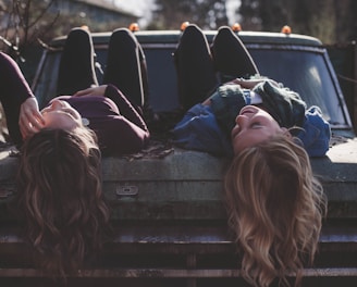 two women lying down on vehicle