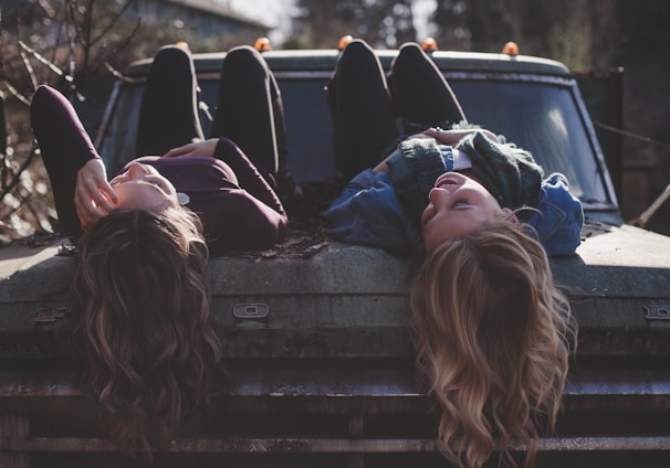 two women lying down on vehicle