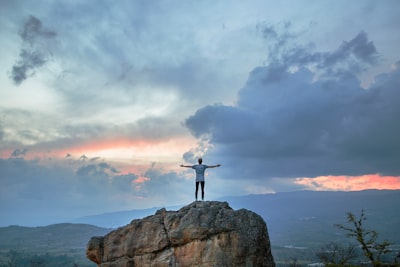 man standing on top of rock mountain during golden hour inspiration teams background