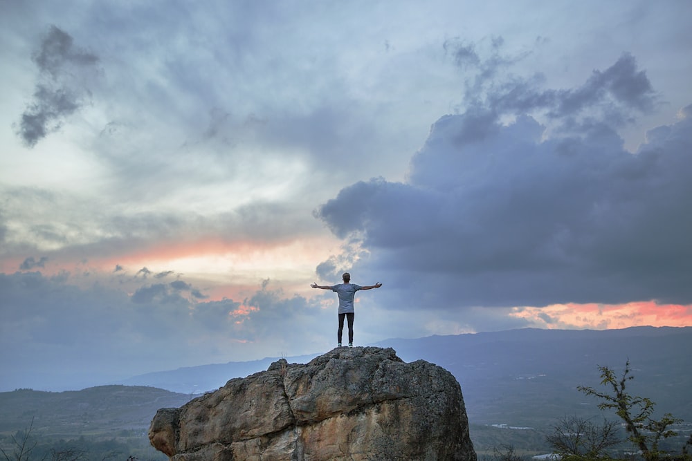 man standing on top of rock mountain during golden hour