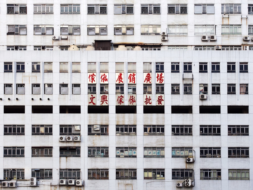 Edificio gris de varios pisos con letreros rojos en escritura oriental