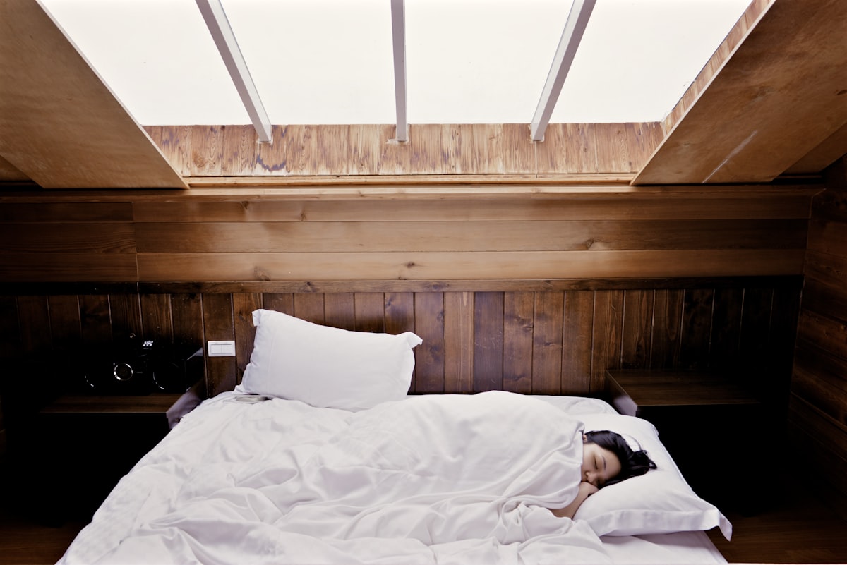 Femme endormie dans un lit sous la lumière douce d'une verrière