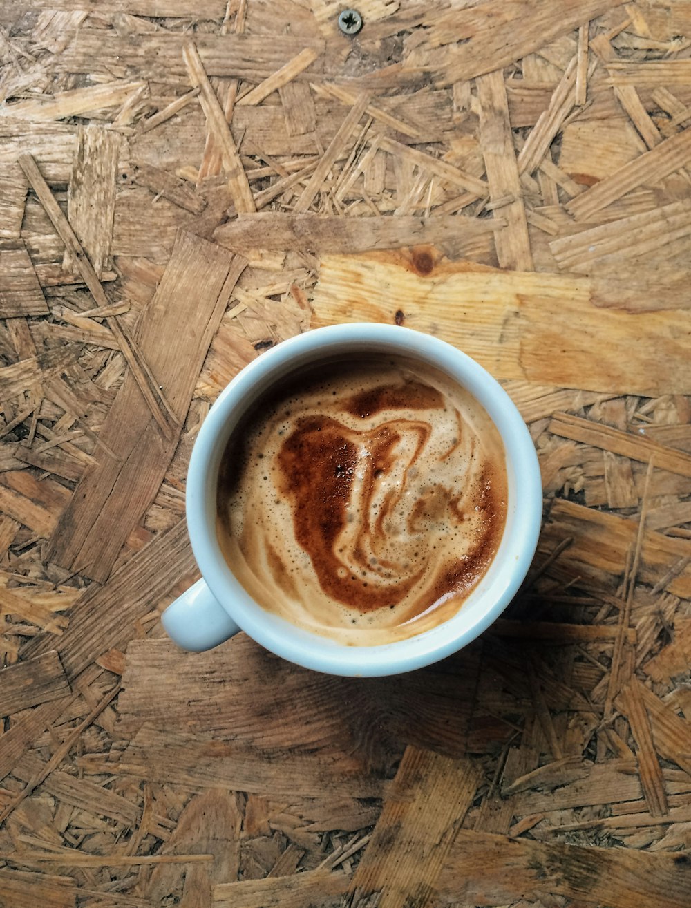 taza de café de cerámica blanca sobre superficie de madera marrón