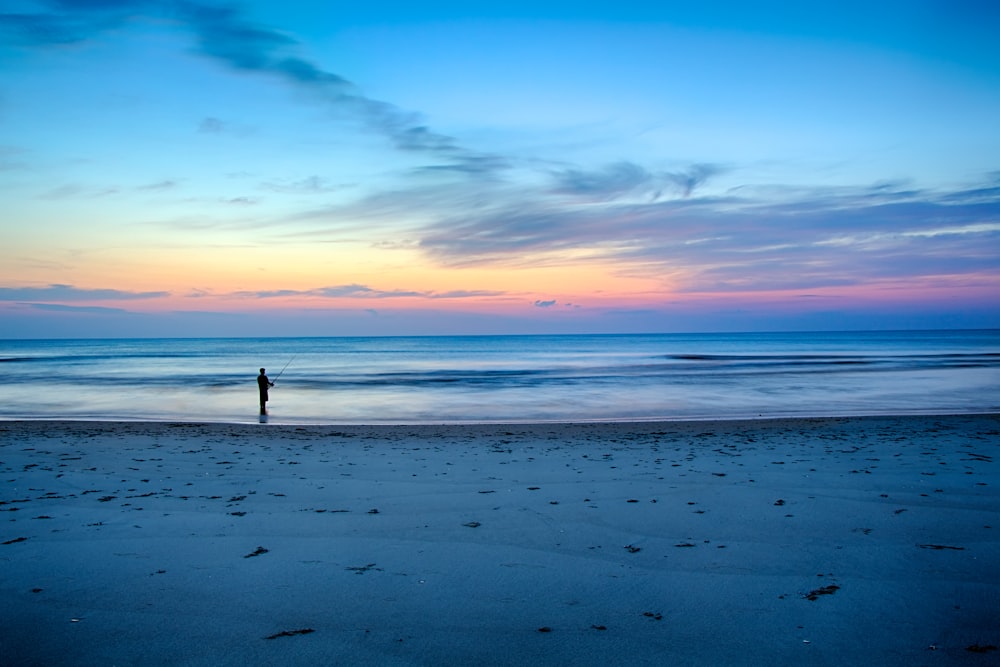 Silhouette einer Person, die auf einem flachen Teil des Meeres fischt