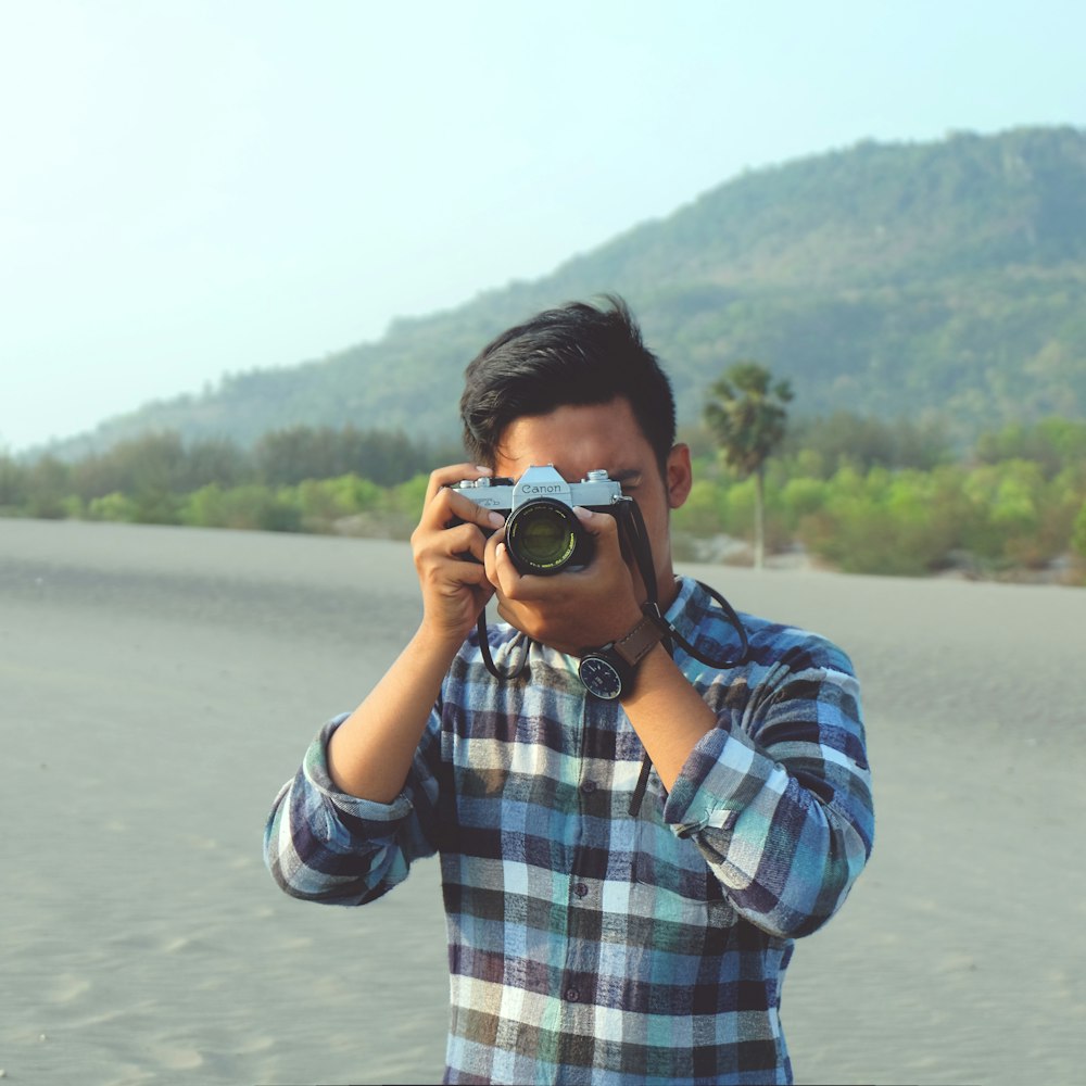 man holding gray and black camera during daytime