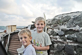 Two brothers smiling proudly in front of freshly painted colorful house walls.