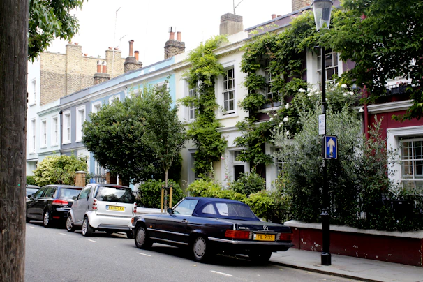 Street view of a row of typical South East England houses used for temporary accommodation, with parked cars and greenery.