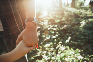 Close-up of a couple's hands intertwined, illuminated by late afternoon sun with earthy color backdrops.