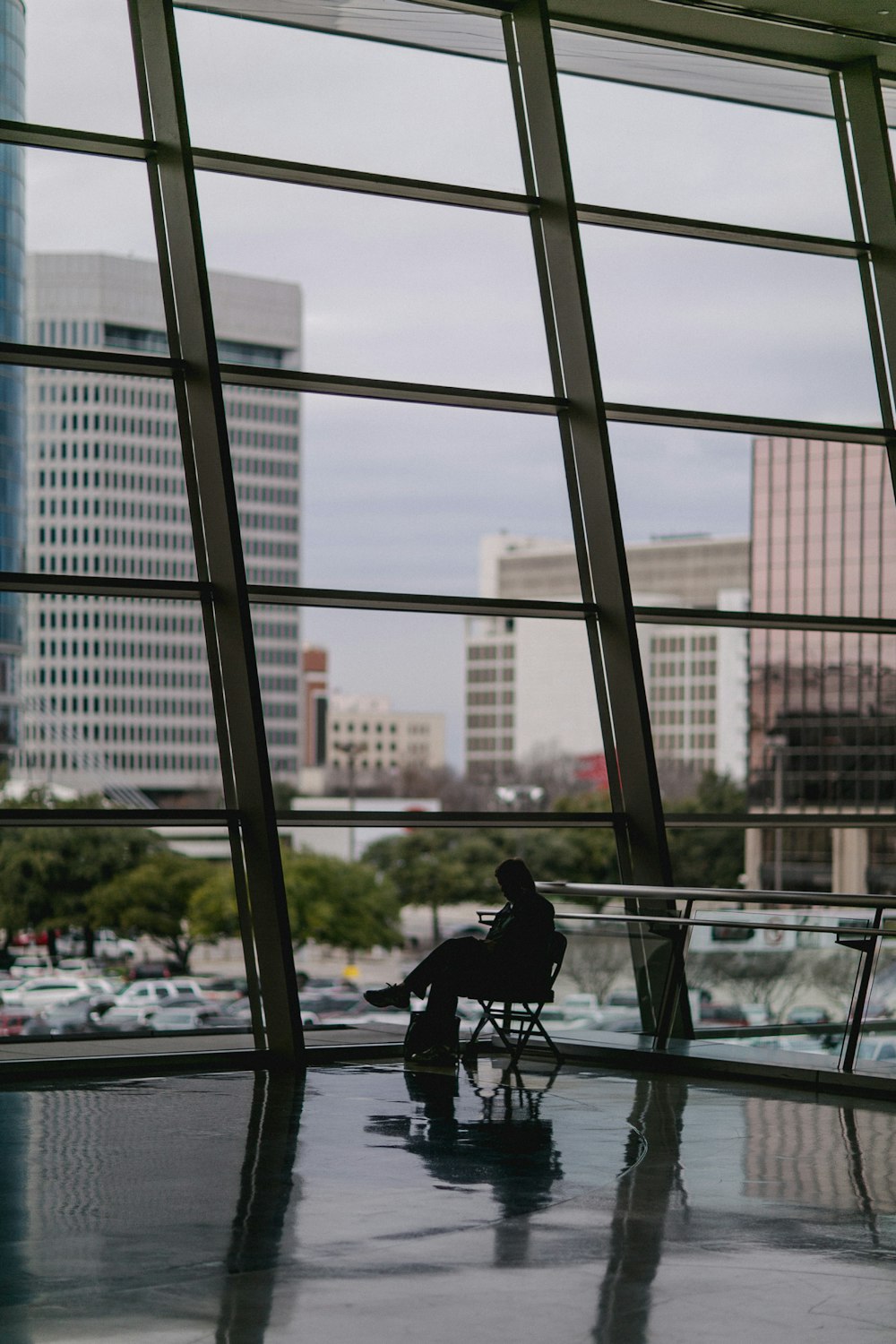 silhouette of person sitting besides clear glass wall inside building