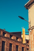 A historic brick building with a pitched roof and several windows is visible. A bright yellow vertical sign with red letters spelling 'LA DÉPÊCHE' is attached to the building. The sky is clear and deep blue, adding contrast and highlighting the architecture.