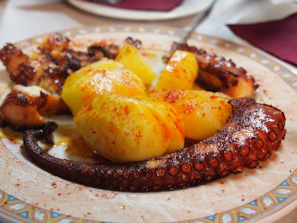 Artfully plated pulpo a la gallega with paprika and olive oil on a white ceramic dish
