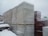 Large pallets covered in plastic wrap are stacked outdoors, all covered with a layer of snow. The scene is set against an overcast sky, suggesting a cold and snowy environment. The ground is not visible, likely under snow, and the pallets appear to be in an industrial or storage area.