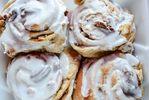 An overhead shot of several cinnamon rolls arranged on a beige linen cloth, bathed in soft natural light.