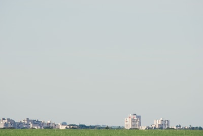 Empty plot of land with clear blue sky and city skyline in the distance