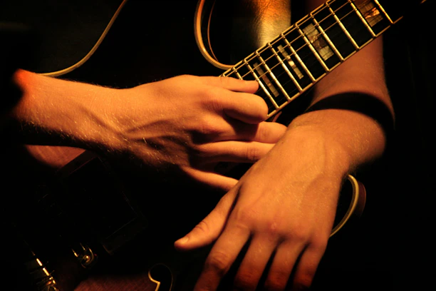 Close-up of a guitarist's hands skillfully playing an electric guitar with metallic gray and black tones.