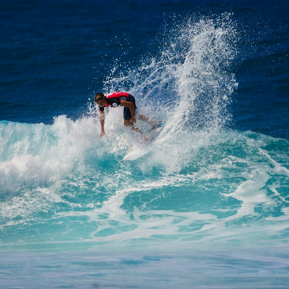 man using surfboard in wave of body of water during daytime