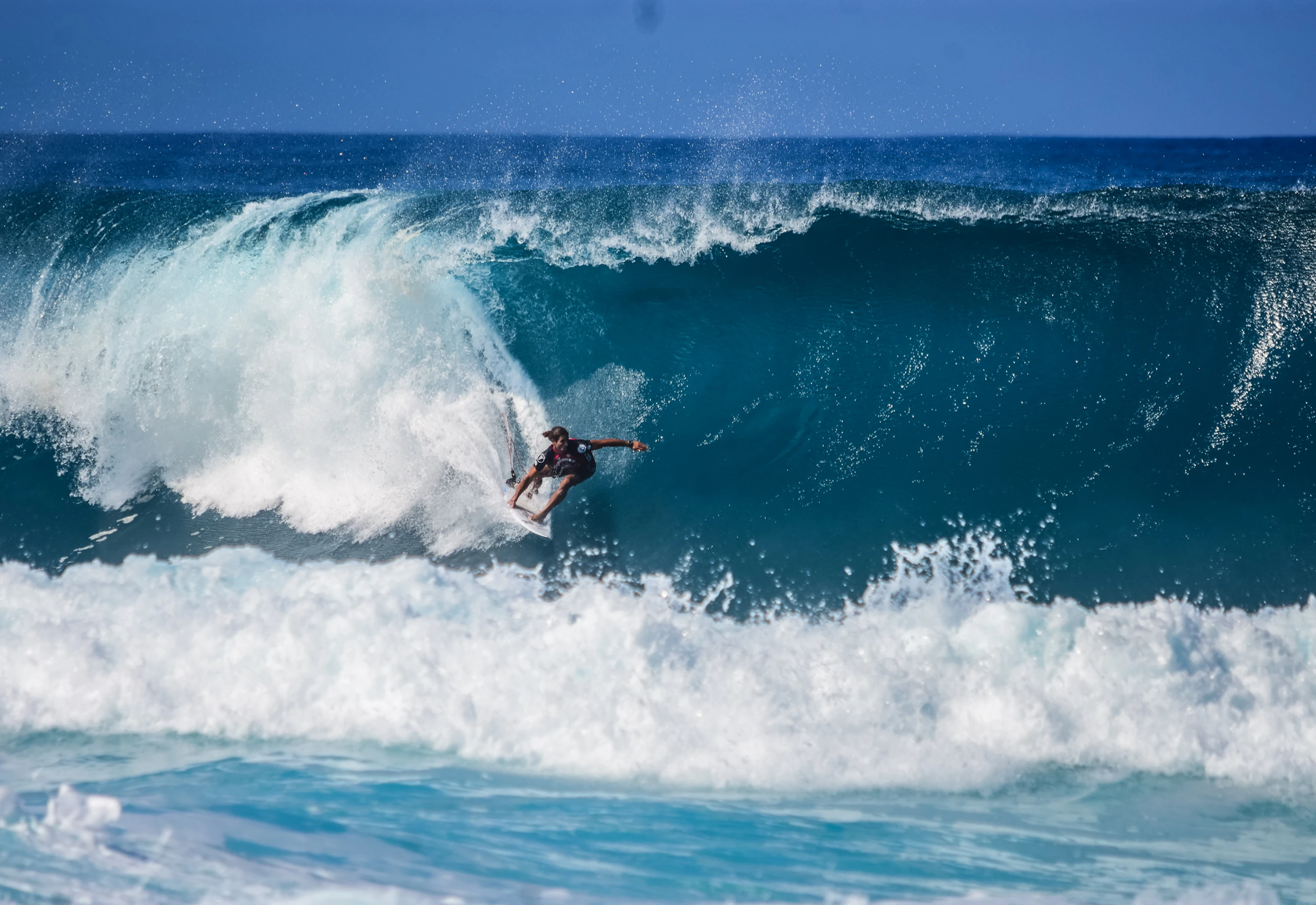 Surfer riding through a powerful blue ocean wave