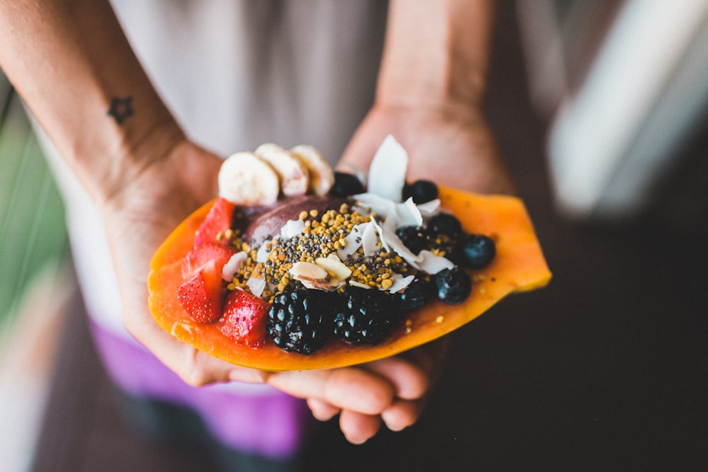 Persona sosteniendo bayas azules con fotografía de enfoque superficial del postre de fresa